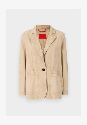 Beige cotton jacket with a notched lapel, single black button closure, two front pockets, and visible stitching details. Red label inside.