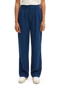 Blauwe gestreepte broek met een losse pasvorm, hoge taille en plooien. Gemaakt van stof met een gladde textuur. Gecombineerd met witte sneakers.
