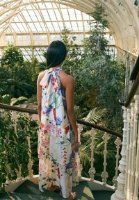Abito con stampa floreale, collo all'americana e silhouette fluida. Presenta colori vivaci tra cui tonalità di rosso, viola e verde.