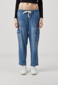 Ljusblå denim cargo-byxor med elastisk midja och snörning. Har tv�å stora sidofickor och en lös, rak passform.