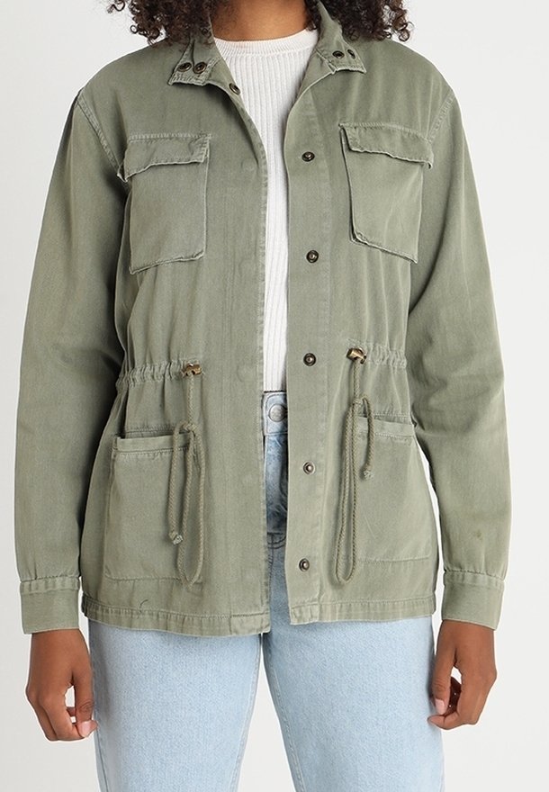 Olive green utility jacket with two chest pockets, drawstring waist, and button closures. Fabric appears textured and durable.