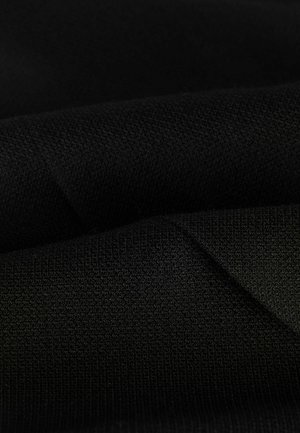 Black fabric with a textured knit pattern, showing folds and creases. Material appears soft and dense, emphasizing a smooth surface.