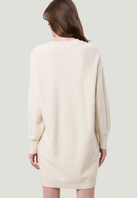 Cremfarbener, übergroßer Pulloverkleid mit langen Ärmeln, gerippten Bündchen und Saum sowie glatter Textur, das eine lässige Silhouette bietet.