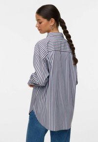 Camicia a righe con colletto, caratterizzata da linee verticali nei toni di blu, rosso e bianco. Vestibilità ampia con orlo curvo e maniche lunghe.
