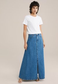 Maksimalus mėlynas džinsinis sijonas, tiesaus kirpimo, su priekine jungtimi ir diržo kilpomis. Susietas su balta marškinėliais trumpomis rankovėmis.