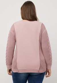 Vaaleanpunainen neulottu villapaita, jossa on vaijeri-neulehihat ja teksturoitu takapaneeli. Ribbattuja hihansuita ja helma, joissa on sivuhalkiot lisäyksiksi.