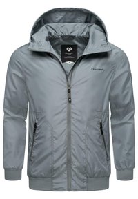 Chaqueta ligera gris con cremallera frontal, capucha y puños acanalados. Presenta bolsillos laterales y un logo en el pecho. Textura suave y brillante.