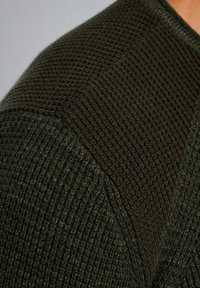 Maglione verde a maglia con un motivo testurizzato che presenta sezioni lisce e a coste a contrasto sulle spalle. Colore verde scuro in tutto il capo.