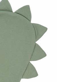Groene gewatteerde kussen in de vorm van een dinosaurus met driehoekige spikes langs de rand. Glad oppervlak en zachte stofafwerking.