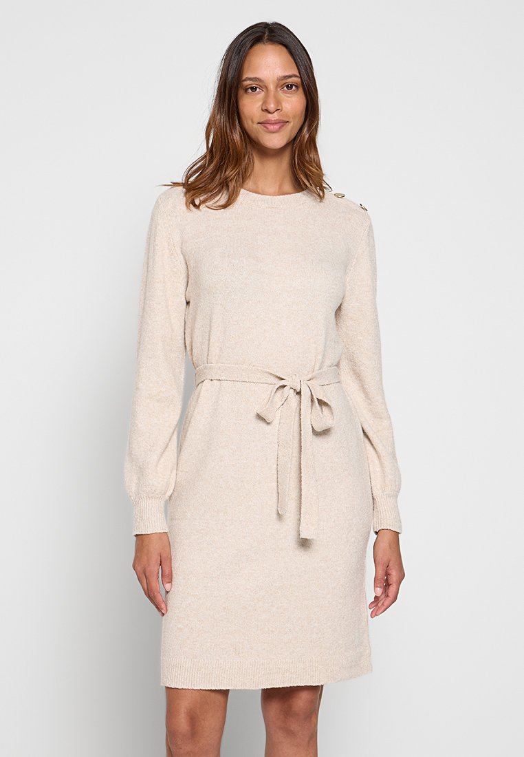 Robe tricotée beige avec des manches longues, un col rond et une ceinture nouée à la taille. Présente des accents de boutons sur l'épaule. Texture douce.