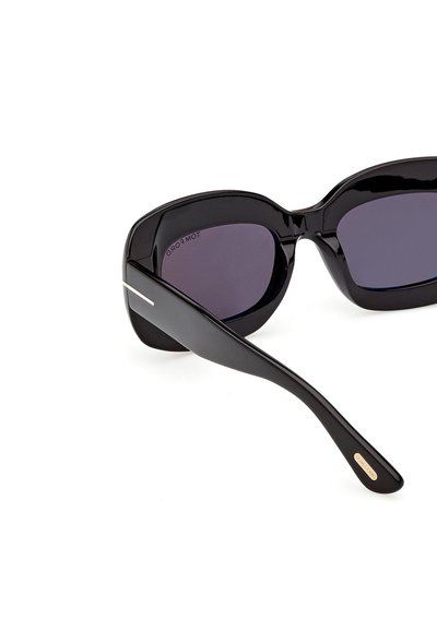 Lunettes de soleil noires surdimensionnées avec des montures épaisses et brillantes, des verres foncés, et la marque "Tom Ford" à l'intérieur de la branche.