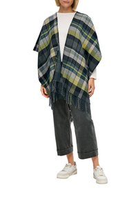 Geruite poncho met franjes, in navy, grijs, olijfgroen en crème kleuren. Draag het over een witte top en combineer het met grijze broek en sneakers.