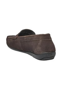 Chaussure en suede brun à enfiler avec un bout arrondi, semelle en caoutchouc noir flexible et coutures le long du bord supérieur.