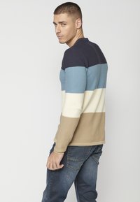 Kötött pulóver vízszintes csíkokkal tengerészkék, világoskék, krémszínű és bézs színben. Rácsos textúra, crew neckline és hosszú ujjú.