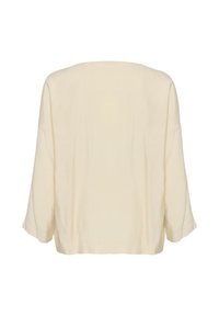Blusa color crema, tessuto leggero, vestibilità ampia, scollatura a barca, spalle scese e maniche a tre quarti. Superficie liscia con una leggera texture.