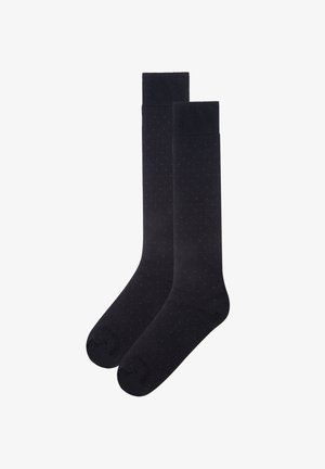 Knielange schwarze Socken mit einer glatten Textur, die ein dezentes Muster aus kleinen roten Punkten aufweisen.
