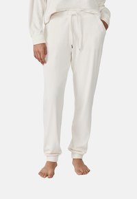 Pantalons de lounge blancs en coton avec une taille élastique et un cordon de serrage, dotés de poches latérales et de poignets ajustés aux chevilles.