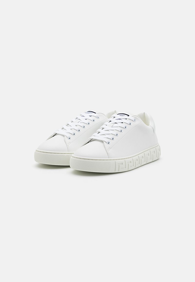 Witte leren sneakers met een glad oppervlak, ronde neus en platte rubberen zool met een patroon aan de zijkant. Gestrikt met contrasterende oogjes.