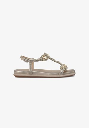 Metallic gouden platte sandalen met een teenlus, versierd met grote kristalaccenten en een gesp sluiting bij de enkelband.