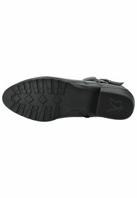 Suela de zapato de cuero negro con un patrón de relieve texturizado, con un tacón cuadrado y un logo en el lado del tacón. Base plana y robusta para tracción.