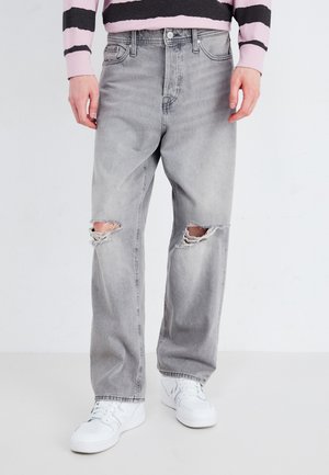 Lysegrå denimjeans med revner på knærne, med en rett ben-design. Brukt med hvite sneakers og en stripete genser.