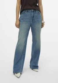 Ljusblå, vida jeans med en blekt finish, fem fickor och bältesöglor. Kombinera med spetiga vita klackar och en mörk topp.