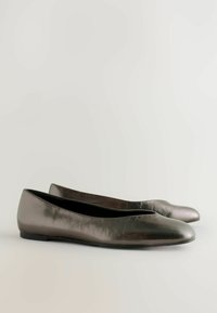 Bailarinas de color gris metálico con una textura suave, punta redondeada y diseño minimalista. Cuentan con un tacón bajo y estilo de calzado fácil de poner.