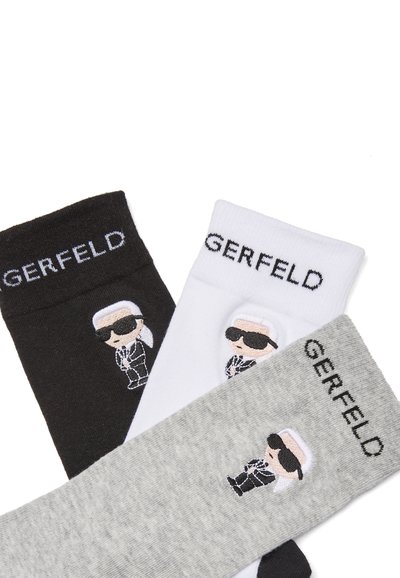 Trois paires de chaussettes de sport en noir, blanc et gris avec des dessins brodés de personnages de dessin animé portant des lunettes de soleil et le mot « GERFELD » sur les bords.