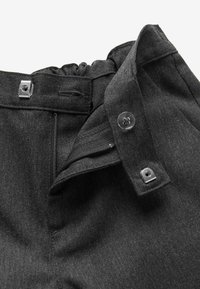Pantalons en denim noir avec une fermeture éclair à l'avant, une fermeture par bouton et des accents en métal. Dotés d'une taille froncée pour l'élasticité et le confort.