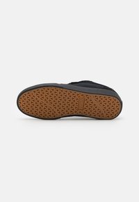 Black sneaker sole featuring a textured rubber bottom with a geometric pattern and brown accents. Reinforced edges provide durability.