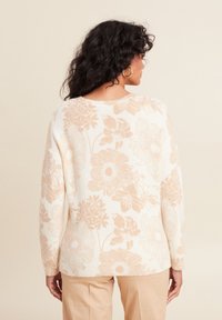 Blumenmuster-Pullover in Creme mit sanften Pfirsichblumen, mit rundem Ausschnitt und langen Ärmeln, aus einem flauschigen Strickmaterial gefertigt.