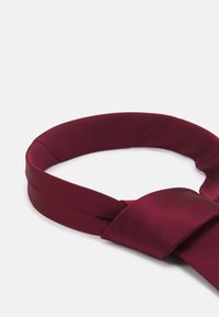 Cravate bordeaux avec une finition texturée, dotée d'un nœud lisse. Le design est classique et élancé, adapté aux occasions formelles.