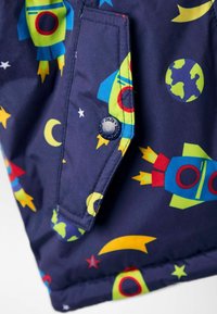 Marineblauer Stoff mit bunten Mustern von Raketen, Planeten, Sternen und Monden. Beinhaltet einen blauen runden Knopf mit der Beschriftung "JoJo."