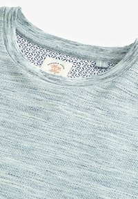 Jasnoniebieski sweter o fakturze z okrągłym dekoltem, z wzorzystym wewnętrznym kołnierzykiem i metką oznaczoną "Durable Goods".