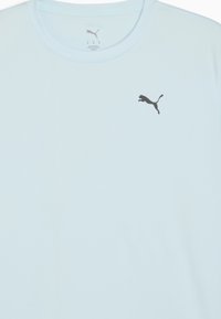 Lyseblå atletisk T-shirt lavet af åndbart stof med rund hals, med et lille sort Puma-logo på brystet.