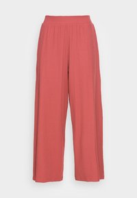 Pantalons larges en tissu doux et texturé. Couleur corail uni avec une taille haute élastique. Présente des plis verticaux pour un détail supplémentaire.