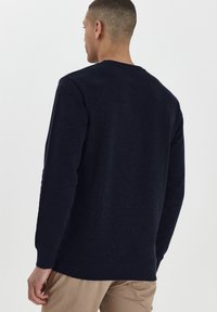 Navyblauwe fleece sweatshirt met een ronde hals, ribgebreide boorden en zoom. Zachte textuur met een casual pasvorm. Achteraanzicht, zonder patronen of grafische elementen.