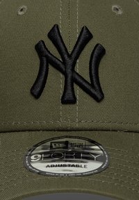 Καπέλο μπέιζμπολ σε ελιά πράσινο χρώμα με κεντημένο μαύρο λογότυπο "NY". Ρυθμιζόμενο μέγεθος με υφή υφάσματος και κυκλικό ταμπελάκι New Era στη γείσο.
