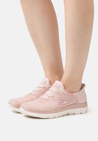 Scarpe da ginnastica rosa chiaro con tomaia in tessuto testurizzato, suola flessibile e branding discreto. Design con lacci e colletto imbottito per il comfort.