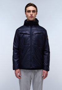 Giacca imbottita blu navy con cappuccio, dotata di zip frontale, due tasche laterali e polsini elasticizzati. Tessuto liscio e lucido, con un logo sulla manica sinistra.