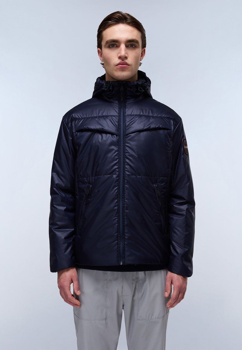 Giacca imbottita blu navy con cappuccio, dotata di zip frontale, due tasche laterali e polsini elasticizzati. Tessuto liscio e lucido, con un logo sulla manica sinistra.