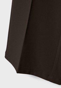 Dark brown fabric close-up showing smooth, slightly textured material with a stitched hem and subtle vertical seam details.