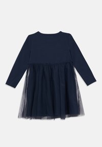 Ναυτικό μπλε φόρεμα με μακριά μανίκια, με στερεό κορσέ και φούστα από στρώσεις τούλι. Το τούλι έχει διάφανο υφή, δημιουργώντας μια παιχνιδιάρικη, ρέουσα εμφάνιση.