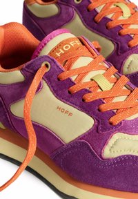 Zapatillas de ante morado y sintético beige con brillantes cordones y acentos de color naranja, presentan un patrón de rejilla texturizado y una suela acolchada.
