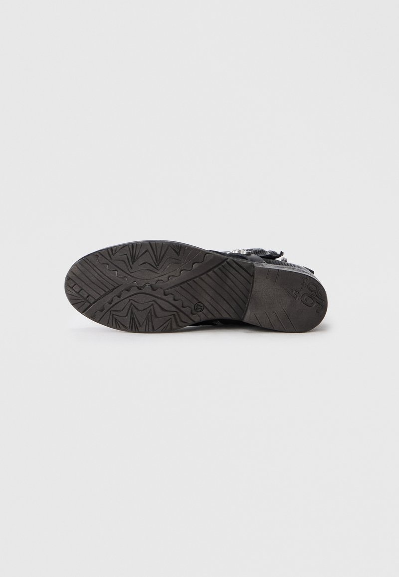 Suela de zapato de goma negra con diseño de banda de rodadura con patrón, que presenta detalles en zigzag y de agarre. Acabado suave con bordes redondeados.