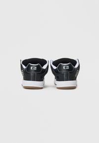 Un paio di sneakers bianche e nere viste da dietro, con suole bianche, collari imbottiti neri e dettagli del logo discreti.
