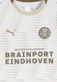 Maglia sportiva bianca con strisce orizzontali, caratterizzata da un collo rotondo marrone, un logo Puma e la scritta "METROPOOLREGIO BRAINPORT EINDHOVEN" in caratteri bold.