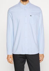 Lichtblauwe overhemd met lange mouwen van katoen, met een button-down kraag, een borstzak en een klein logo aan de bovenkant links.