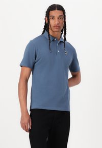 Μπλε πόλο μπλούζα από βαμβάκι με κοντά μανίκια, τριπλό κουμπί και λογότυπο στη θήκη του στήθους. Λείος υφασμάτινος τύπος, κομψή εφαρμογή.