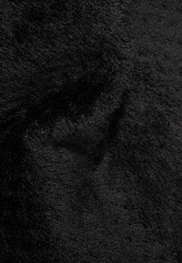 Tessuto nero con una texture morbida e pelosa, caratterizzato da una superficie liscia e una leggera lucentezza. Il materiale appare denso e vellutato.
